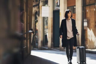 Traveller strolling through the city with her hand luggage.