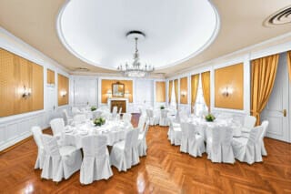 Festlich geschmückter Goldener Festsaal im Hotel Atlantic Hamburg. Vier runde Tische sind für jeweils 10 Personen im Galaformat eingedeckt.