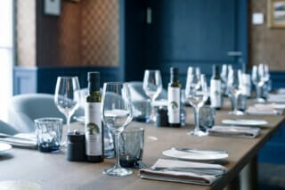 Elegant gedeckter Tisch mit Gläsern, Olivenöl und Geschirr in stilvollem Restaurant.