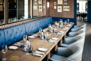 Eleganter Essbereich mit blauen Polstern, gedecktem Tisch und stilvollem Ambiente.