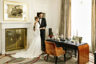 Ein Hochzeitspaar in einer stilvollen Suite, die für eine private und exklusive Feier vorbereitet ist. Das Paar steht an einem elegant gedeckten Tisch für zwei Personen. Der Tisch ist mit feinem Geschirr, edlen Gläsern geschmückt, was eine intime und romantische Atmosphäre schafft. Die Suite strahlt Eleganz und Exklusivität aus, perfekt für ein unvergessliches Hochzeitsdinner in privater Zweisamkeit.