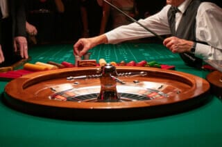 Roulette-Tisch und Dealer mit Spielern im Hintergrund