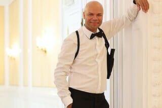 Dennis Durant lehnt lässig an der Tür vom Goldenen Saal, thematisch für den James Bond Abend gekleidet, Holster mit Waffe unter seinem Arm
