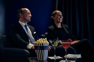 Zwei Personen genießen Cocktails und Popcorn in einer eleganten Lounge-Umgebung.