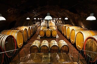 Fasslagerraum mit großen Holzfässern in einem historischen Weingut. Dunkle Beleuchtung.