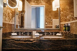 Elegantes Badezimmer mit marmoriertem Waschbecken, Spiegel und modernen Lichtquellen.