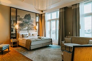 Luxuriöses Hotelzimmer mit modernem Dekor, großen Fenstern und Blick auf die Stadt.